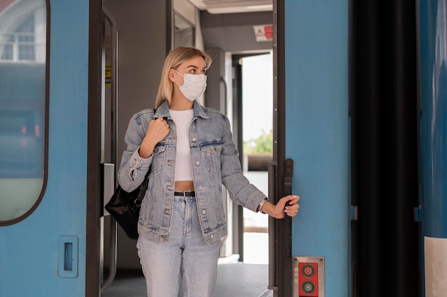 Vrouw die met de trein reist en een medisch masker draagt voor bescherming