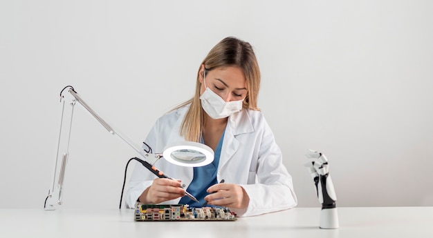 Gratis foto vrouw die met gezichtsmasker bij bureau werkt