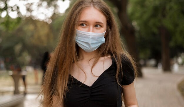 Vrouw die met gezichtsmasker in het park loopt