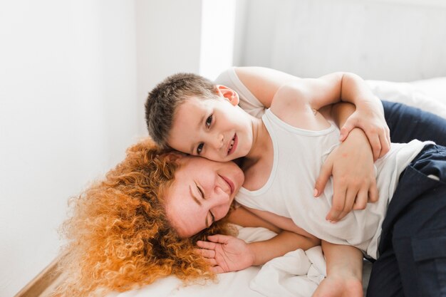 Vrouw die met haar zoon op bed ligt