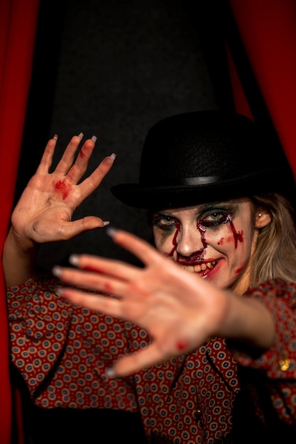 Gratis foto vrouw die met halloween-jokermake-up camera en het verbergen bekijken