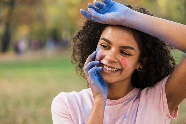 Vrouw die met handen glimlacht die in blauw poeder worden behandeld