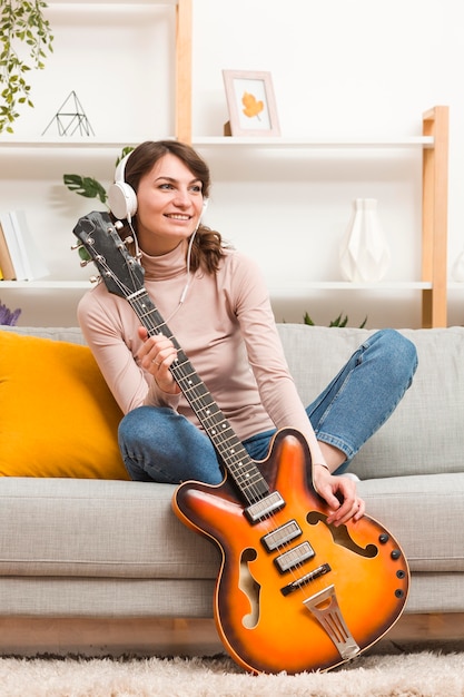 Vrouw die met hoofdtelefoons gitaar houdt