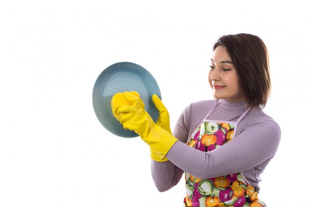 Vrouw die met kleurrijke schort een schotel wast