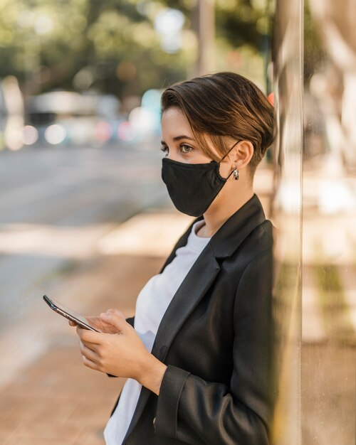 Vrouw die met medisch masker haar telefoon controleert