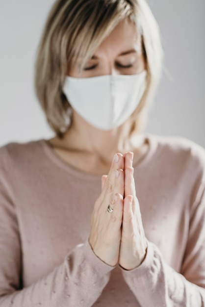 Gratis foto vrouw die met medisch masker thuis bidt