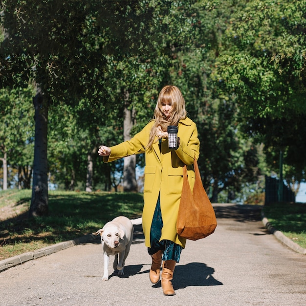 Gratis foto vrouw die met thermosflessen met hond loopt