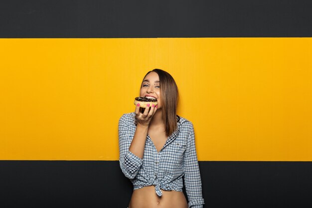 Vrouw die met witte heldere glimlach smakelijke doughnut eet.