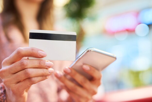 Vrouw die mobiele telefoon en creditcard gebruikt tijdens online winkelen