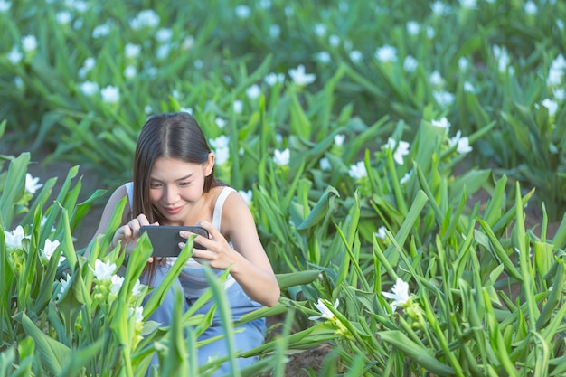 Vrouw die mobiele telefoon met behulp van om foto in de bloementuin te maken.