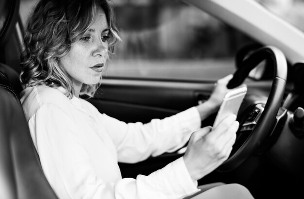 Vrouw die mobiele telefoon met behulp van tijdens het rijden