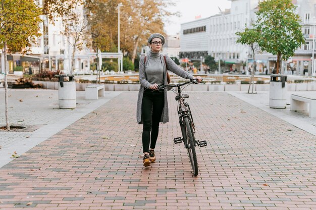 Vrouw die naast haar fiets loopt