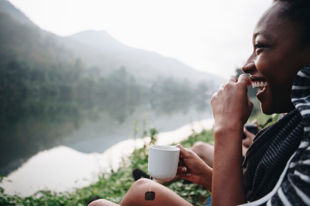 Vrouw die ochtendkoffie vangt door een rivier