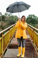 Gratis foto vrouw die op brug een paraplu houdt