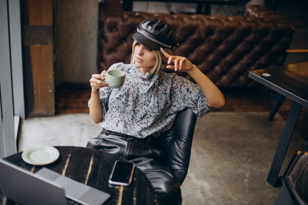 Vrouw die op de computer werkt en koffie drinkt