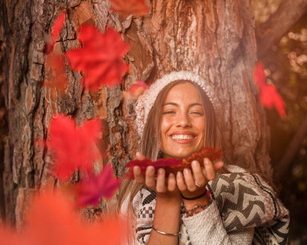 Vrouw die op de herfstbladeren blaast en lacht