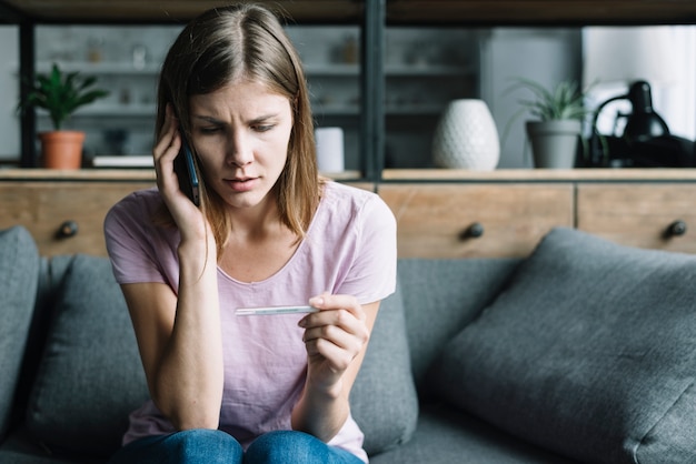 Vrouw die op de thermometer van de cellphoneholding spreekt