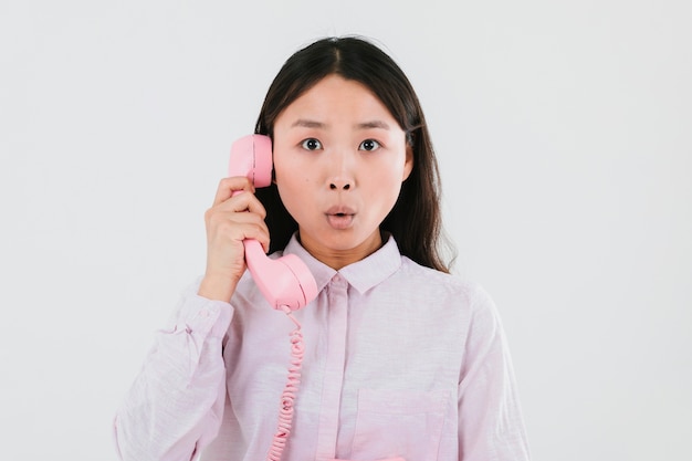 Gratis foto vrouw die op een roze telefoon spreekt