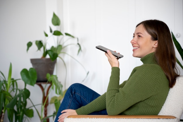 Vrouw die op haar smartphone praat terwijl ze thuis is en de handsfree-functie gebruikt