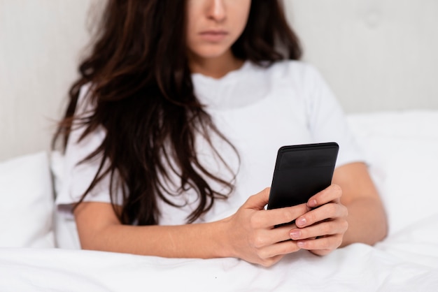 Vrouw die op haar telefoonclose-up kijkt