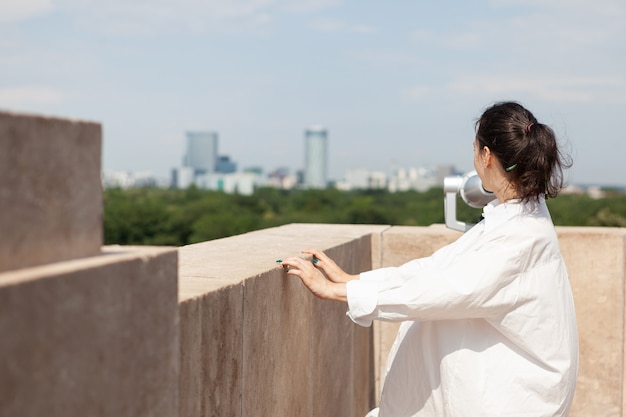 Vrouw die op het dak van de toren staat en geniet van de zomervakantie en kijkt naar panoramisch uitzicht