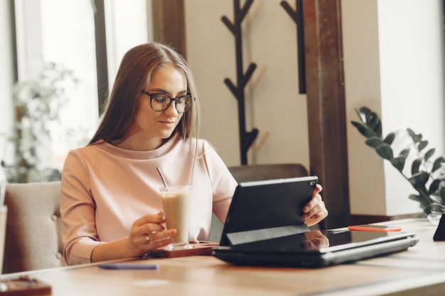 Vrouw die op kantoor werkt. Dame met een tablet. Vrouw in een witte blouse.