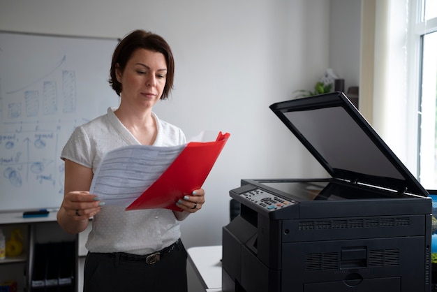 Vrouw die op kantoor werkt en printer gebruikt