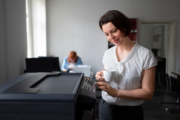 Vrouw die op kantoor werkt en printer gebruikt