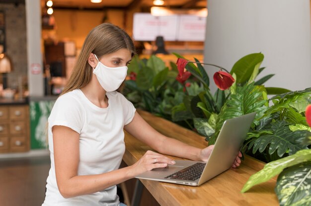 Vrouw die op laptop met masker werkt