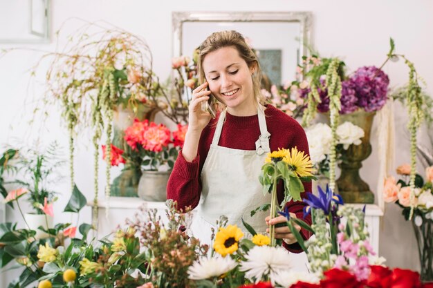 Vrouw die op smartphone in bloemenwinkel spreekt