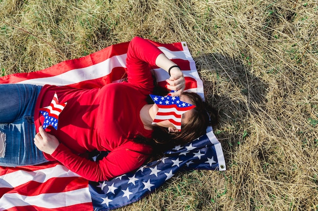 Vrouw die op stof van Amerikaanse vlag op gebied ligt