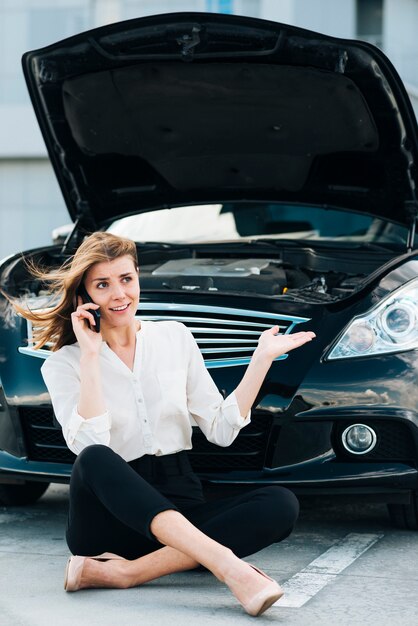 Vrouw die op telefoon en zwarte auto spreekt