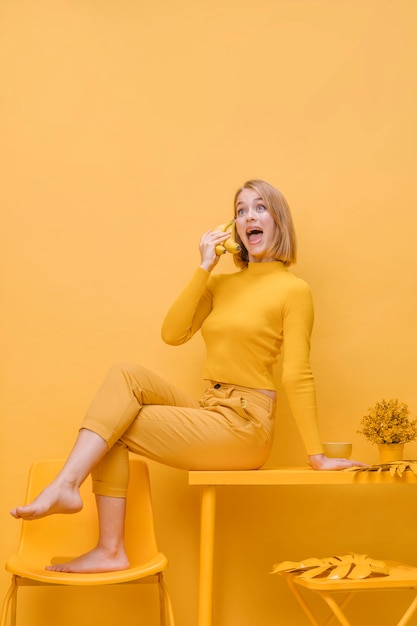 Vrouw die op telefoon in een gele scène spreekt