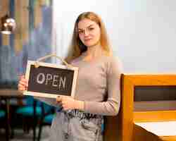 Gratis foto vrouw die open teken voor koffiewinkel houdt