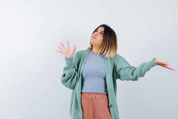 Vrouw die palm toont, palm opzij spreidt in vrijetijdskleding en hoopvol, vooraanzicht kijkt.