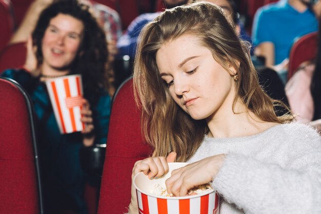 Vrouw die popcorn van emmer grijpt