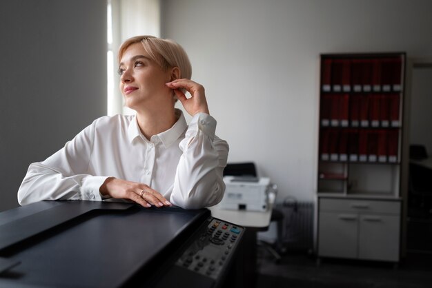 Vrouw die printer gebruikt terwijl ze op kantoor werkt