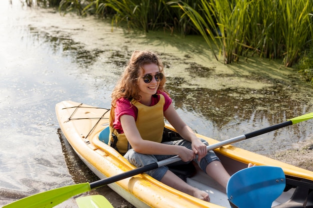 Gratis foto vrouw die reddingsvest draagt dat in kajak verblijft