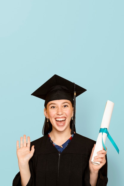 Gratis foto vrouw die regalia draagt met haar diploma voor afstuderen