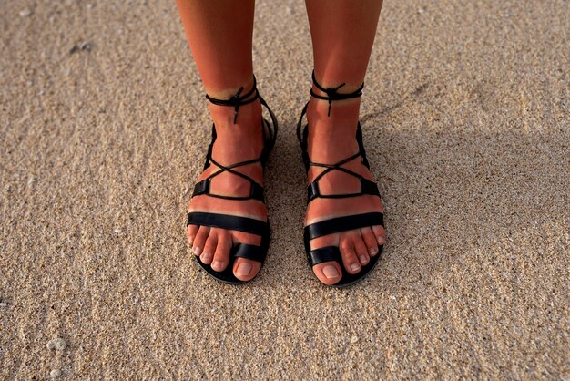 Vrouw die Romeinse sandalen draagt op het strand