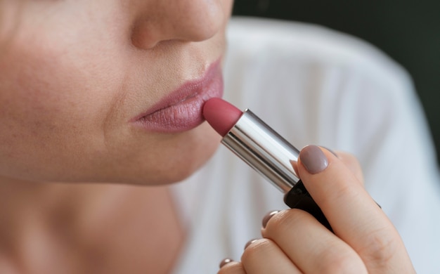 Vrouw die roze lippenstift op haar lippen toepast