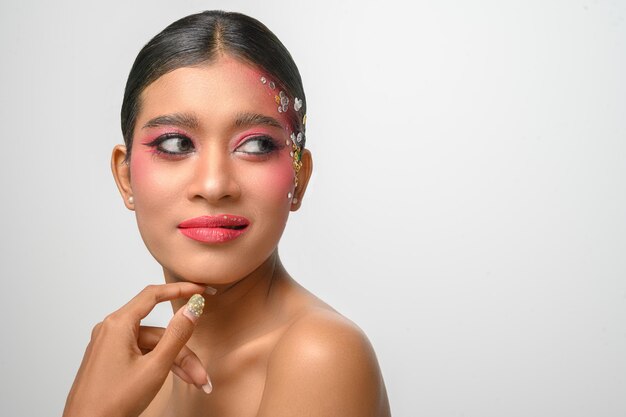 Vrouw die roze make-up en versieringen op haar gezicht draagt dat op wit wordt geïsoleerd