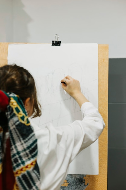 Gratis foto vrouw die schets op schildersezel maakt