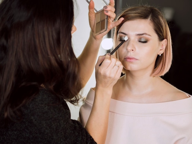 Vrouw die schoonheidsmiddelen op model toepast