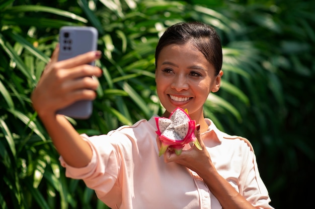 Vrouw die selfie met smartphone neemt terwijl ze drakenfruit eet