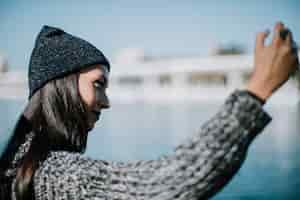 Gratis foto vrouw die selfie met water op achtergrond nemen