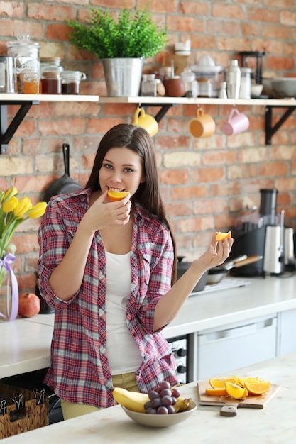 Vrouw die sinaasappelen in de keuken eet