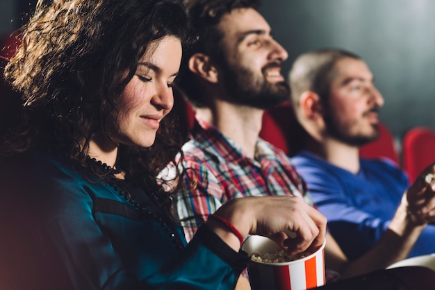 Vrouw die smakelijke popcorn in bioskoop eet