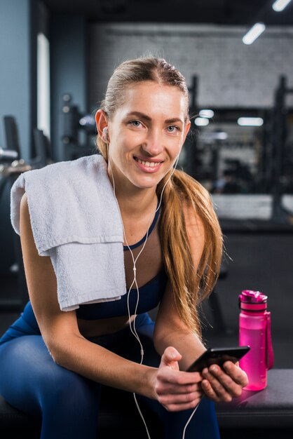 Vrouw die smartphone in gymnastiek gebruikt