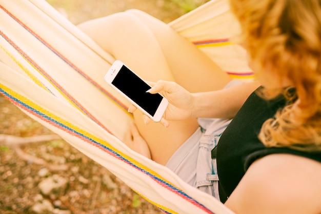 Vrouw die smartphone in hangmat gebruikt